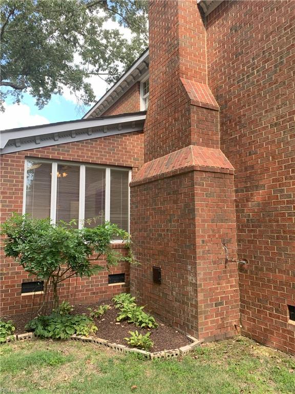 view of home's exterior featuring crawl space, brick siding, a chimney, and a sunroom