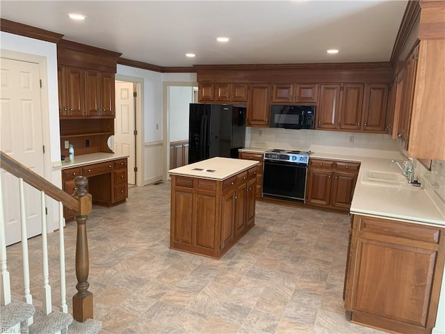 kitchen with a sink, black appliances, light countertops, wainscoting, and a center island