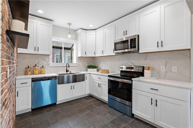 kitchen with backsplash, light countertops, appliances with stainless steel finishes, white cabinets, and a sink