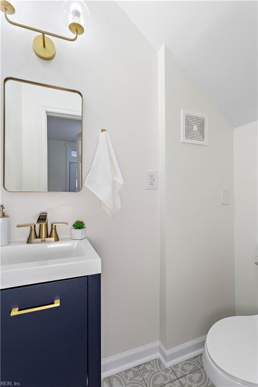 bathroom featuring visible vents, toilet, baseboards, vanity, and vaulted ceiling