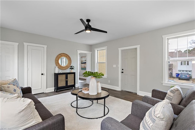 living area featuring dark wood finished floors, a ceiling fan, and baseboards