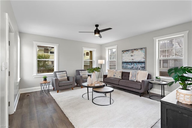 living area featuring visible vents, baseboards, ceiling fan, and dark wood-style flooring