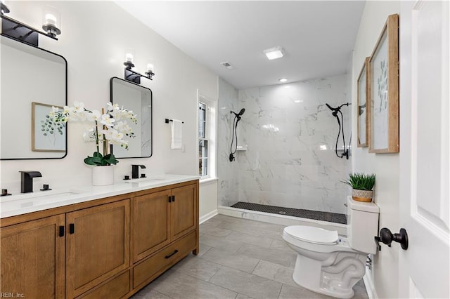 full bath featuring double vanity, tiled shower, toilet, and a sink