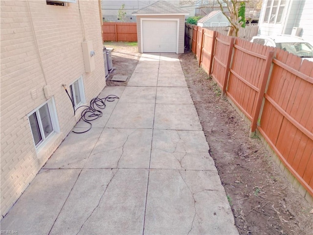 view of patio / terrace with an outbuilding, a garage, driveway, and a fenced backyard