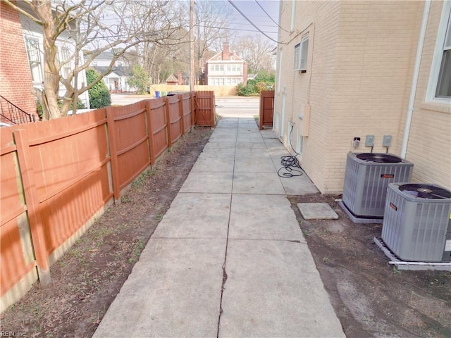 view of property exterior with brick siding, a patio area, central AC unit, and fence