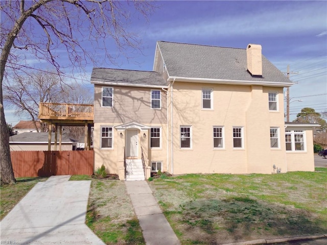 view of front of house featuring fence, roof with shingles, a front yard, stucco siding, and a chimney