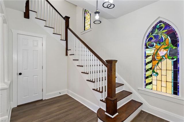 staircase with a towering ceiling, baseboards, and wood finished floors