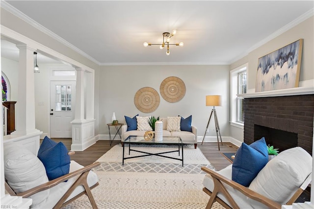 living room with decorative columns, baseboards, wood finished floors, and crown molding