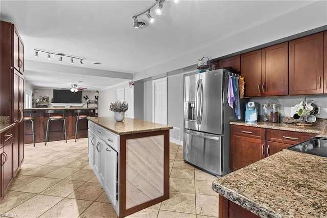 kitchen with open floor plan, a center island, light tile patterned flooring, and stainless steel refrigerator with ice dispenser