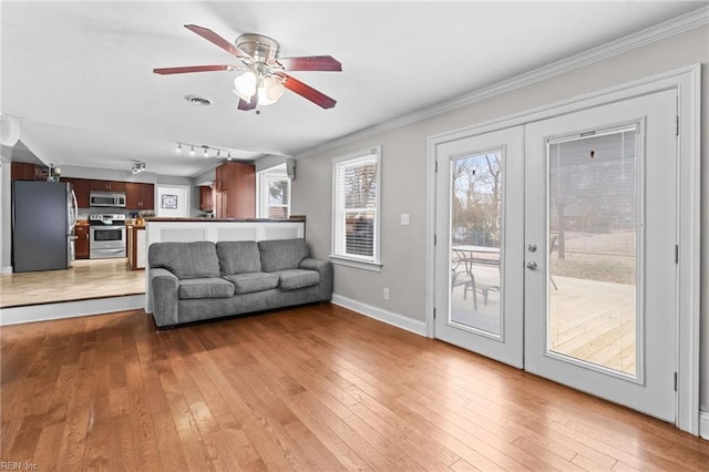 unfurnished living room featuring baseboards, crown molding, a ceiling fan, and hardwood / wood-style flooring