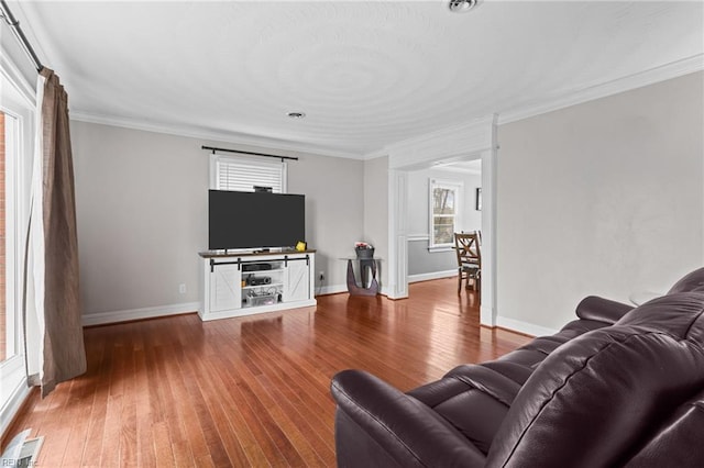 living room featuring hardwood / wood-style flooring, baseboards, visible vents, and ornamental molding