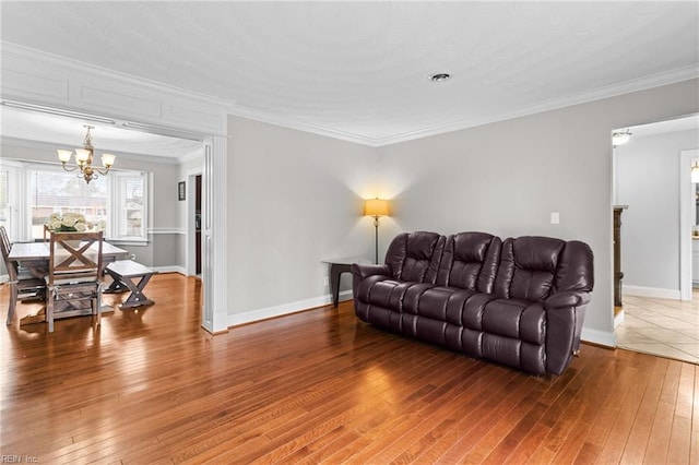 living room featuring baseboards, an inviting chandelier, ornamental molding, and hardwood / wood-style flooring