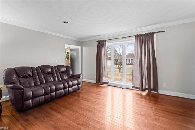 living area featuring hardwood / wood-style floors, baseboards, visible vents, and ornamental molding