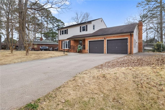 view of front of property with brick siding, driveway, a chimney, and a garage