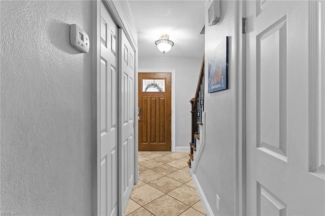 hallway featuring light tile patterned floors, stairs, and baseboards