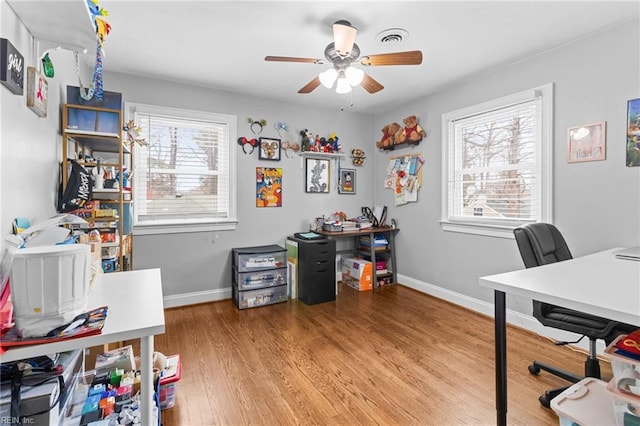 office area with light wood finished floors, visible vents, a healthy amount of sunlight, and a ceiling fan