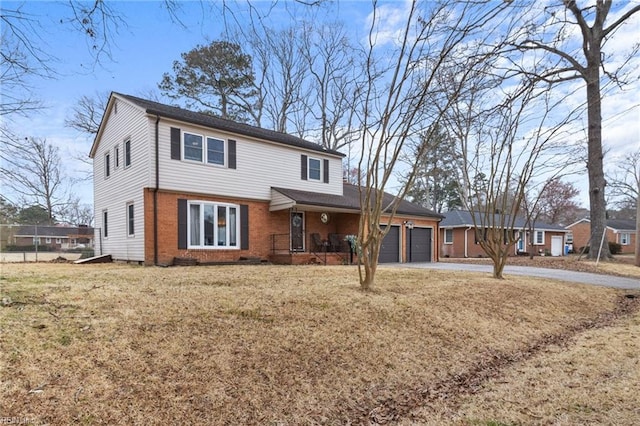 view of front of property featuring driveway, a front yard, brick siding, and an attached garage