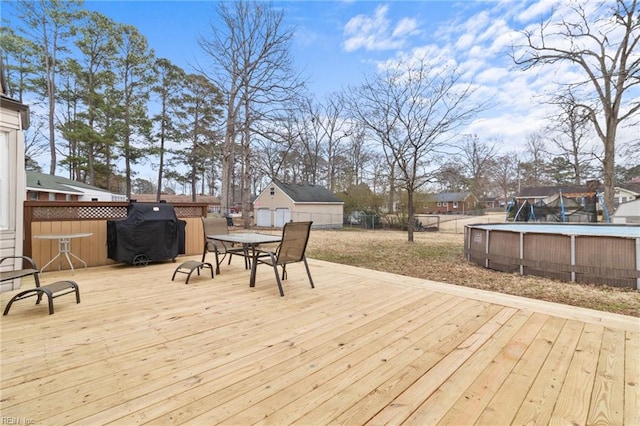 wooden terrace featuring an outdoor structure, fence, an outdoor pool, and a grill