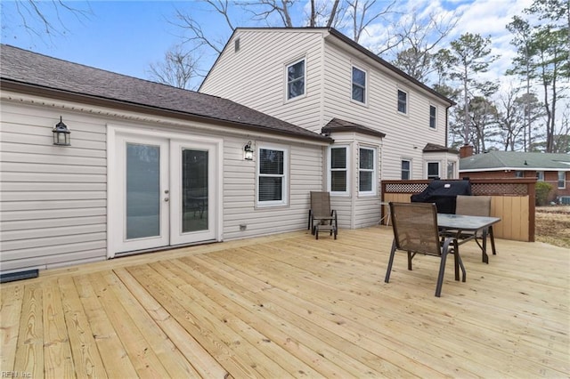 wooden terrace with outdoor dining space, french doors, and grilling area