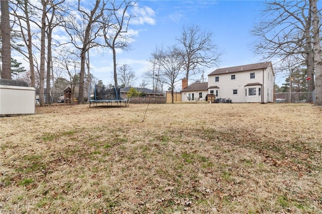 view of yard featuring an outbuilding, a shed, a trampoline, and fence