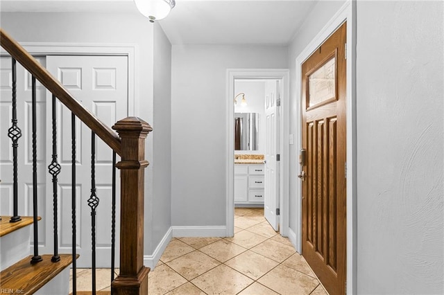 corridor featuring light tile patterned floors, stairway, and baseboards