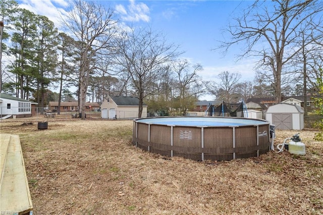 view of yard with an outbuilding, a shed, an outdoor pool, and fence