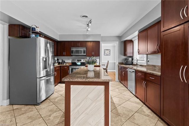 kitchen with light tile patterned floors, stone countertops, stainless steel appliances, and a sink