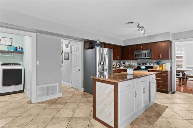 kitchen featuring visible vents, washer / clothes dryer, light tile patterned flooring, and stainless steel appliances