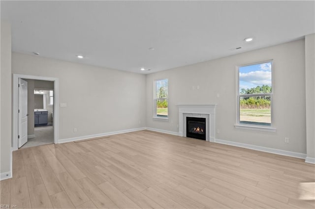 unfurnished living room with light wood finished floors, recessed lighting, and baseboards