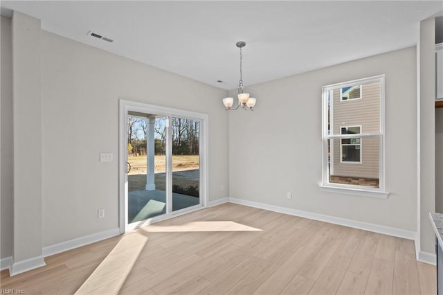 spare room with light wood-type flooring, visible vents, baseboards, and a chandelier