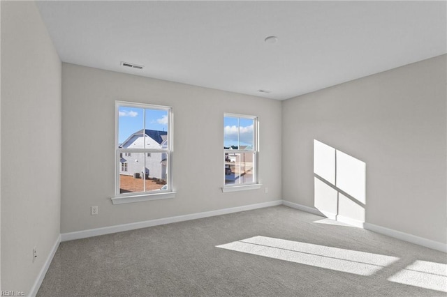 carpeted empty room featuring visible vents and baseboards