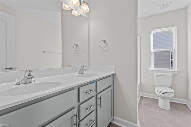 bathroom with double vanity, toilet, baseboards, and a sink