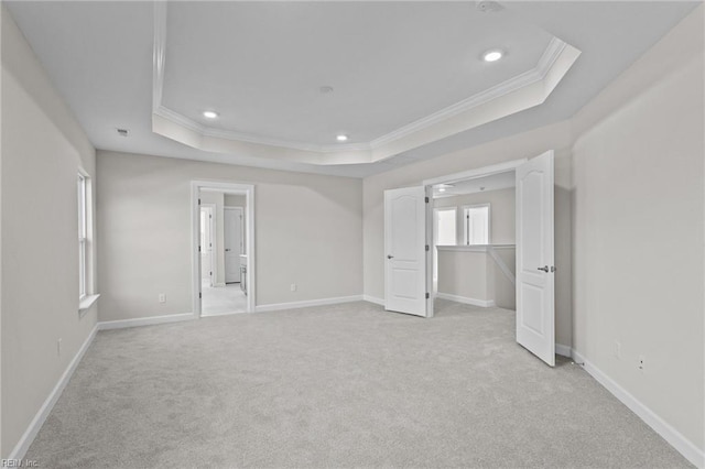 unfurnished bedroom with a tray ceiling, crown molding, and light colored carpet