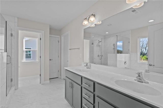 full bathroom with double vanity, marble finish floor, a shower stall, and a sink