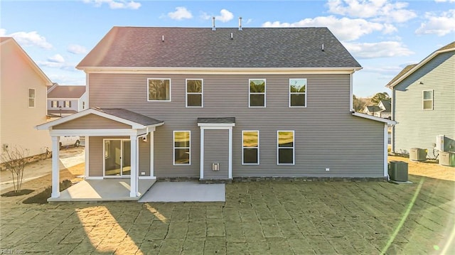 rear view of property with central AC unit, a patio area, and a shingled roof