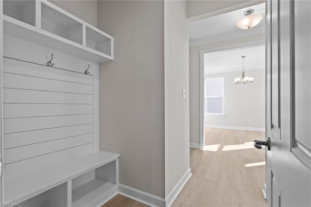 mudroom with ornamental molding, light wood-style floors, baseboards, and a chandelier