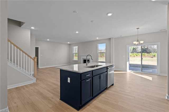 kitchen featuring dishwasher, open floor plan, light wood finished floors, and a sink