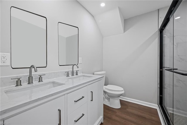 bathroom featuring toilet, wood finished floors, a marble finish shower, and a sink