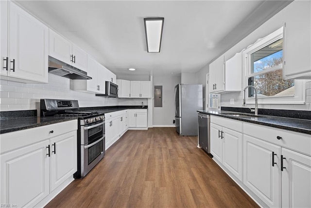 kitchen featuring tasteful backsplash, under cabinet range hood, appliances with stainless steel finishes, white cabinets, and a sink