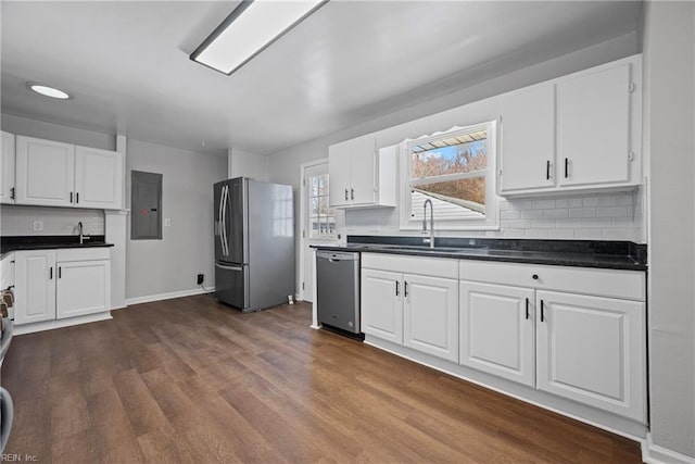 kitchen featuring dark countertops, stainless steel appliances, dark wood-style floors, white cabinetry, and a sink