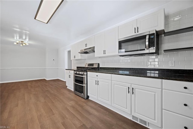 kitchen featuring visible vents, dark wood finished floors, stainless steel appliances, decorative backsplash, and under cabinet range hood