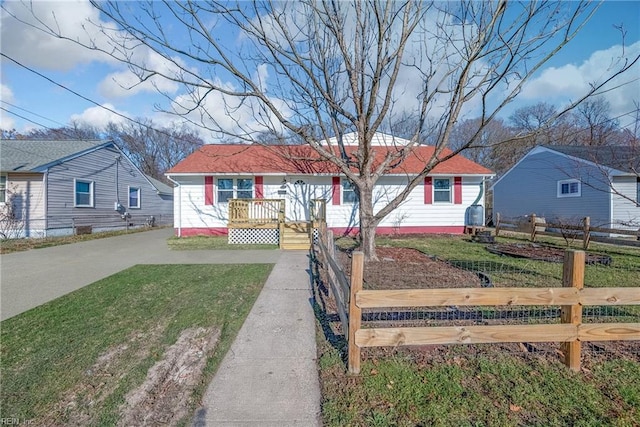 view of front facade featuring a front yard, driveway, and fence