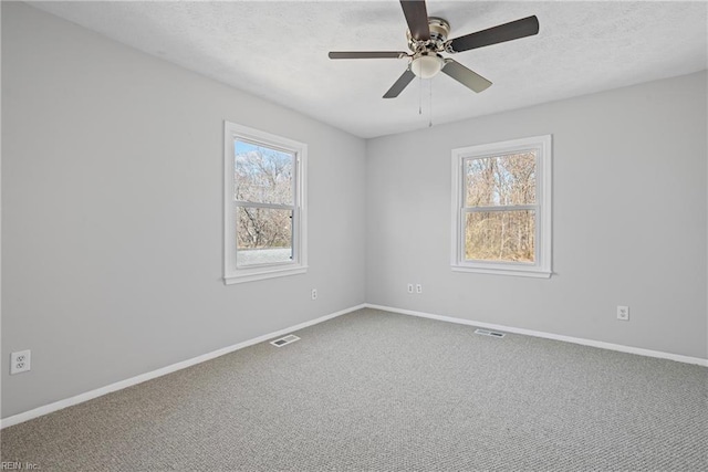 unfurnished room with visible vents, a healthy amount of sunlight, and carpet floors