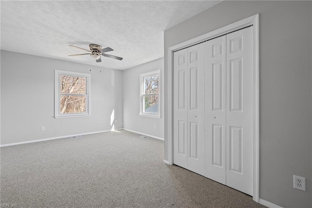 unfurnished bedroom featuring ceiling fan, baseboards, carpet flooring, a closet, and a textured ceiling