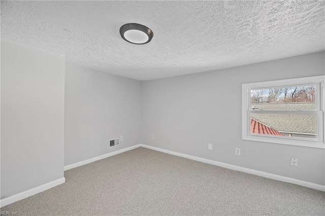 carpeted spare room featuring visible vents, baseboards, and a textured ceiling