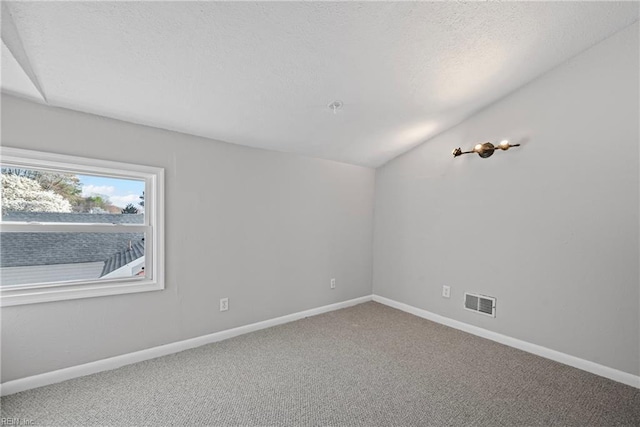 carpeted spare room featuring lofted ceiling, baseboards, visible vents, and a textured ceiling