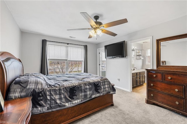 bedroom featuring visible vents, ensuite bathroom, a ceiling fan, baseboards, and light colored carpet