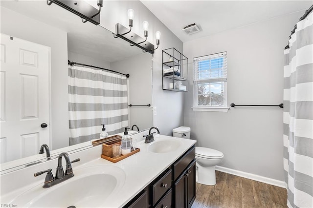 bathroom featuring visible vents, toilet, wood finished floors, and a sink