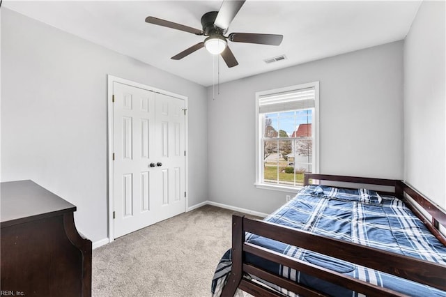 carpeted bedroom featuring visible vents, baseboards, a closet, and a ceiling fan