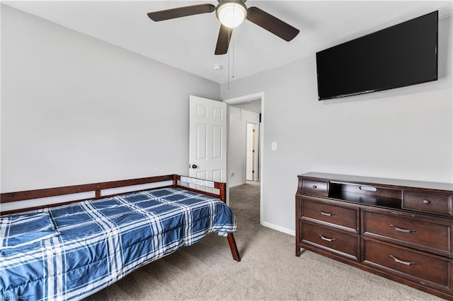 bedroom featuring baseboards, light colored carpet, and ceiling fan